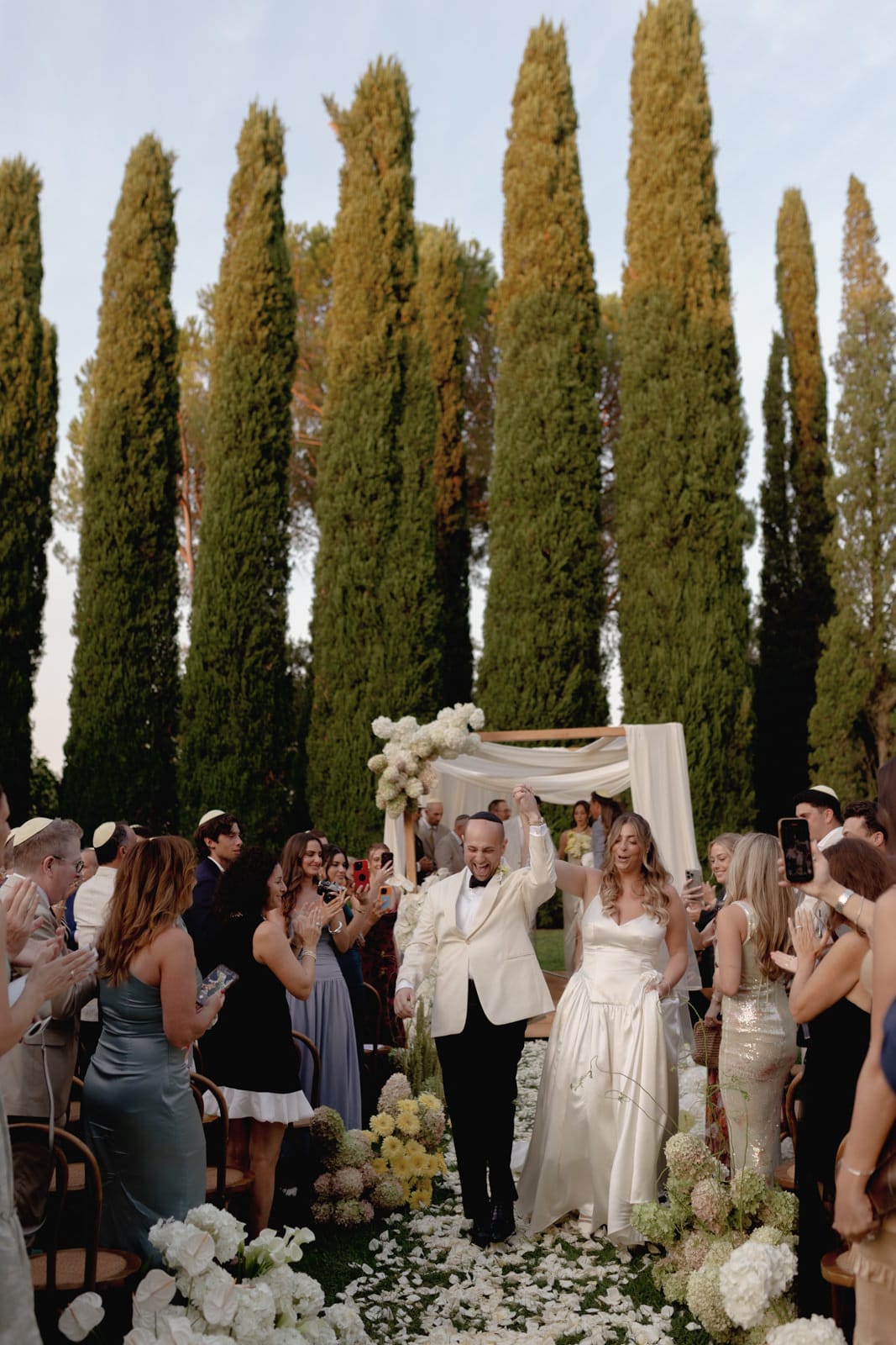 A man and woman dancing under a canopy of flowers.