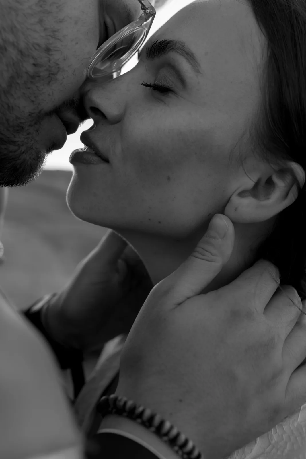 Kind Words 7 A close-up black-and-white photo of two people about to kiss, with one person gently holding the others neck and both having their eyes closed, capturing an intimate, romantic moment.